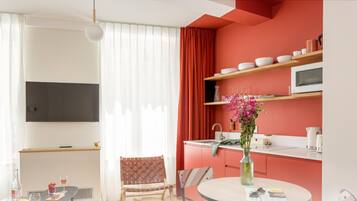 A modern kitchen with white countertops, a microwave, and a red accent wall.