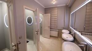 Een moderne badkamer met drie wastafels, een grote spiegel en een badkamermeubel met een radiator.