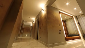 Een moderne hotelgang met een marmeren vloer, houten accenten en inbouwverlichting.