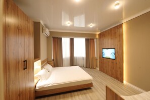 A modern hotel room with a large bed, wooden panel walls, a flat-screen TV, and a ceiling-mounted air conditioner. - Cozy Hostel (Bishkek)