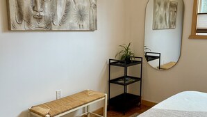 A bedroom with a bed, a bench, a shelf with a plant, and two wall-mounted artworks. - Su Casa Suite with Sauna (Salmo)