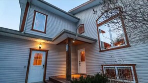 A two-story house with a front porch, a door with a window, and a small set of steps leading to the entrance. - Su Casa Suite with Sauna (Salmo)