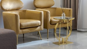 Una habitación con dos sillones dorados y una mesita redonda de base dorada.