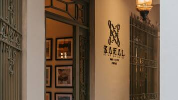 A hotel entrance with a tiled floor, a hanging light fixture, and a wall-mounted sign.