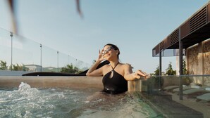 Una persona en traje de baño negro en una piscina cristalina con un moderno fondo arquitectónico.