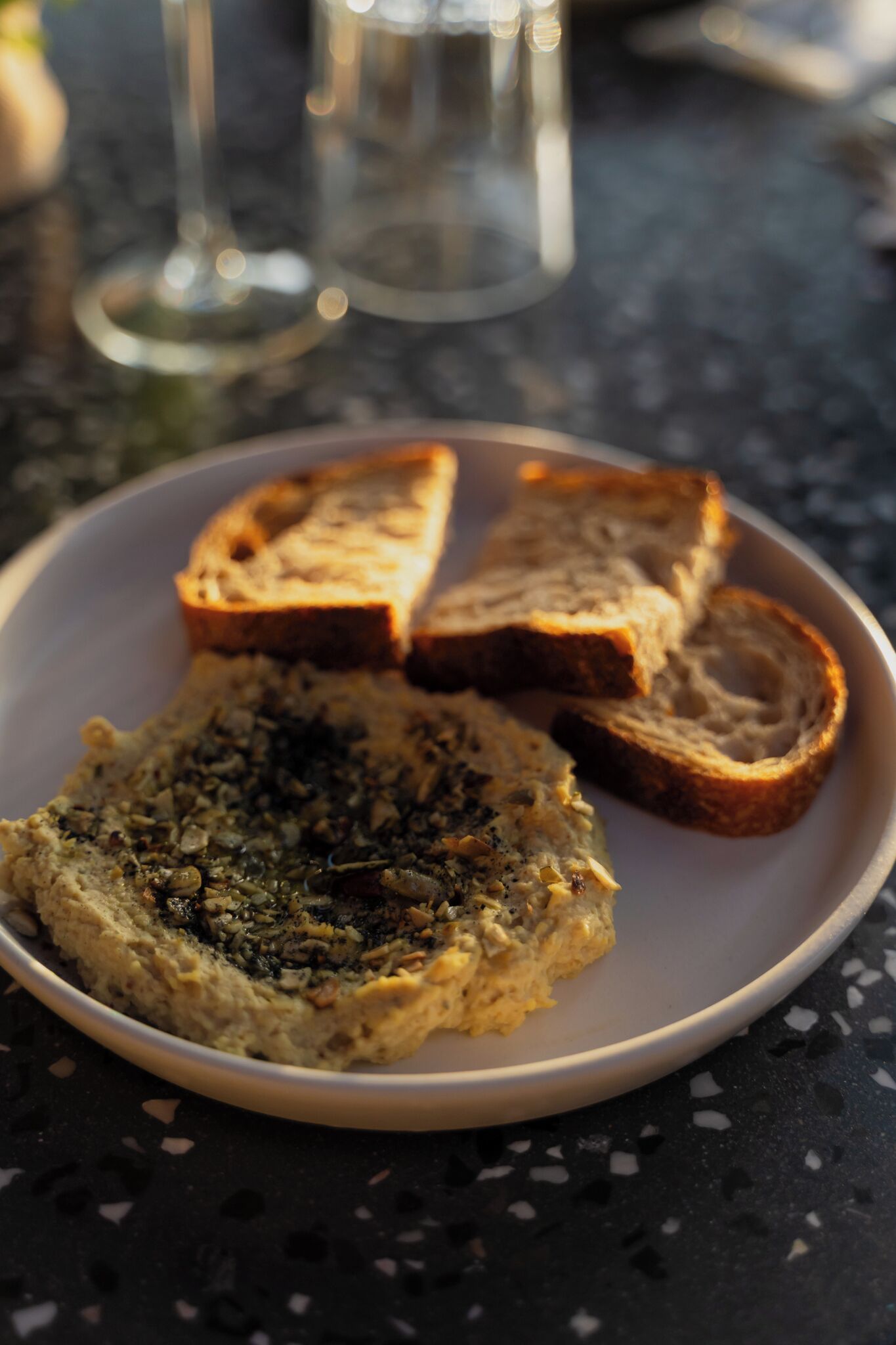 A plate with a spread and two slices of bread on a dark table.