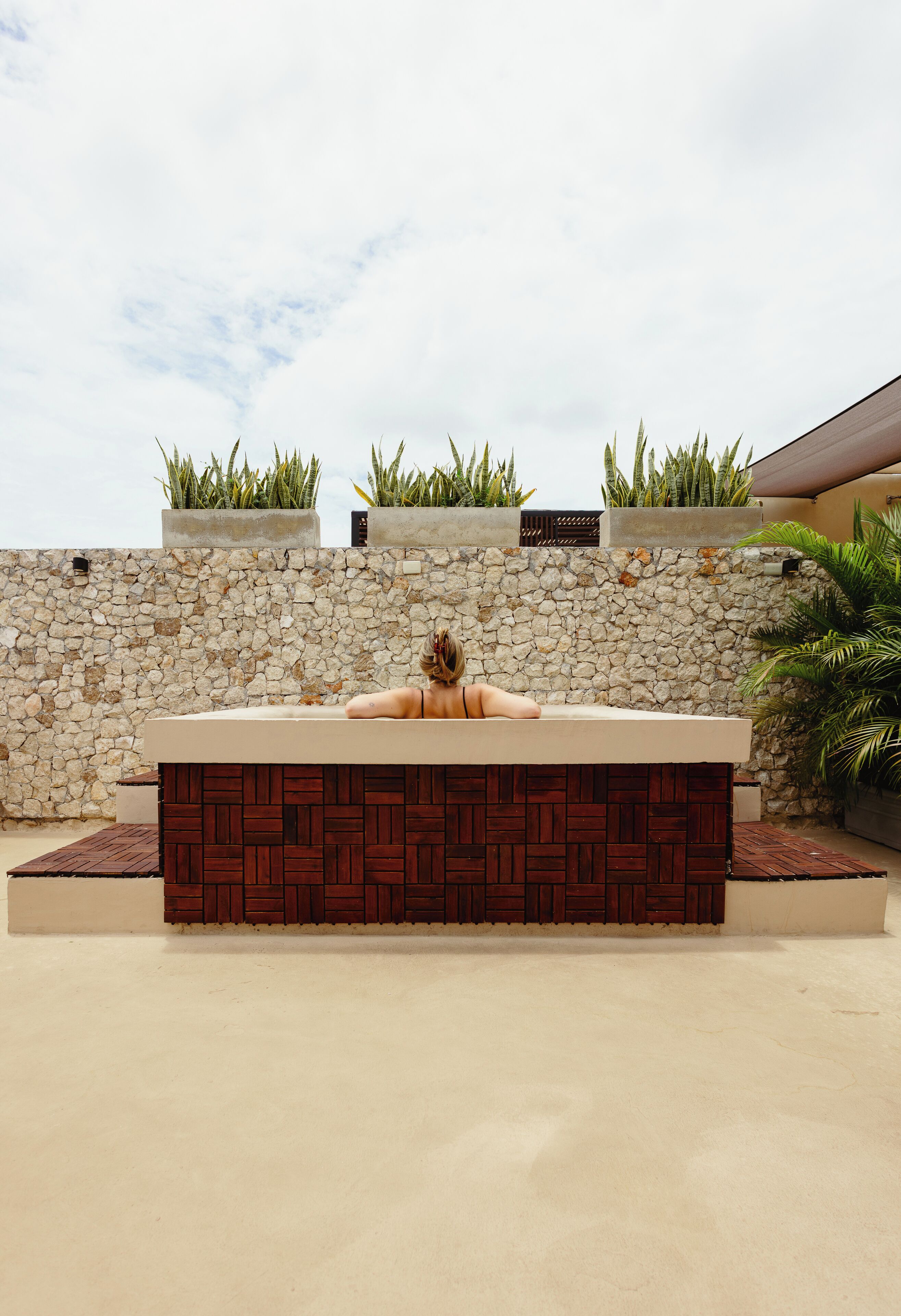 A spa area with a stone wall, wooden paneling, and potted plants.