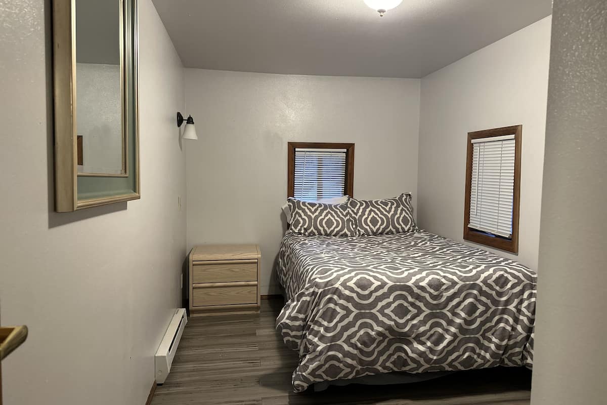 A bedroom with a bed, bedside tables, a mirror, and a ceiling light.