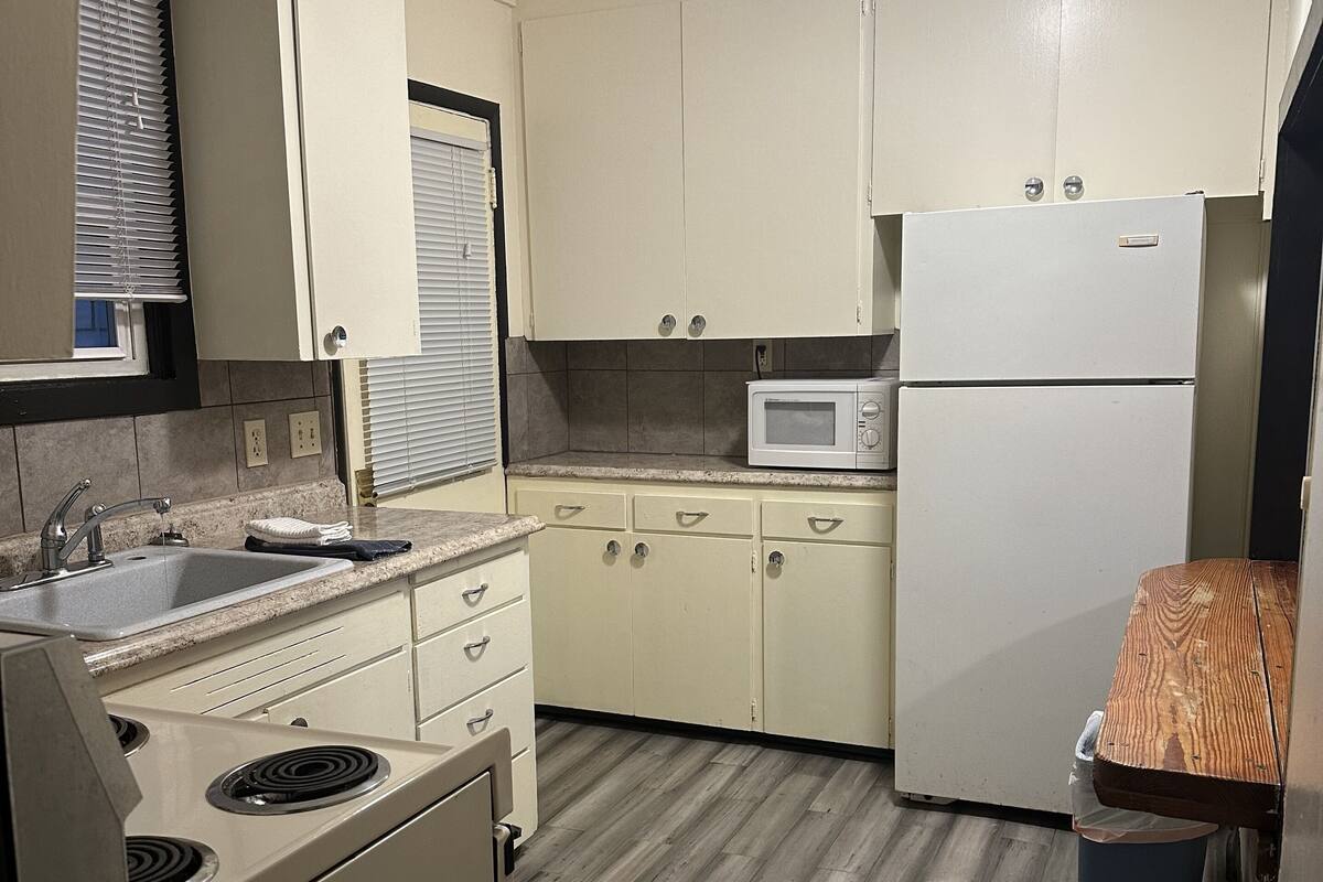 A compact kitchen with a sink, stove, microwave, and refrigerator.