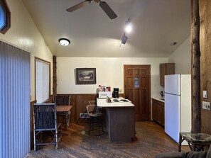 A kitchen with a central island, wooden cabinets, a refrigerator, and a ceiling fan.