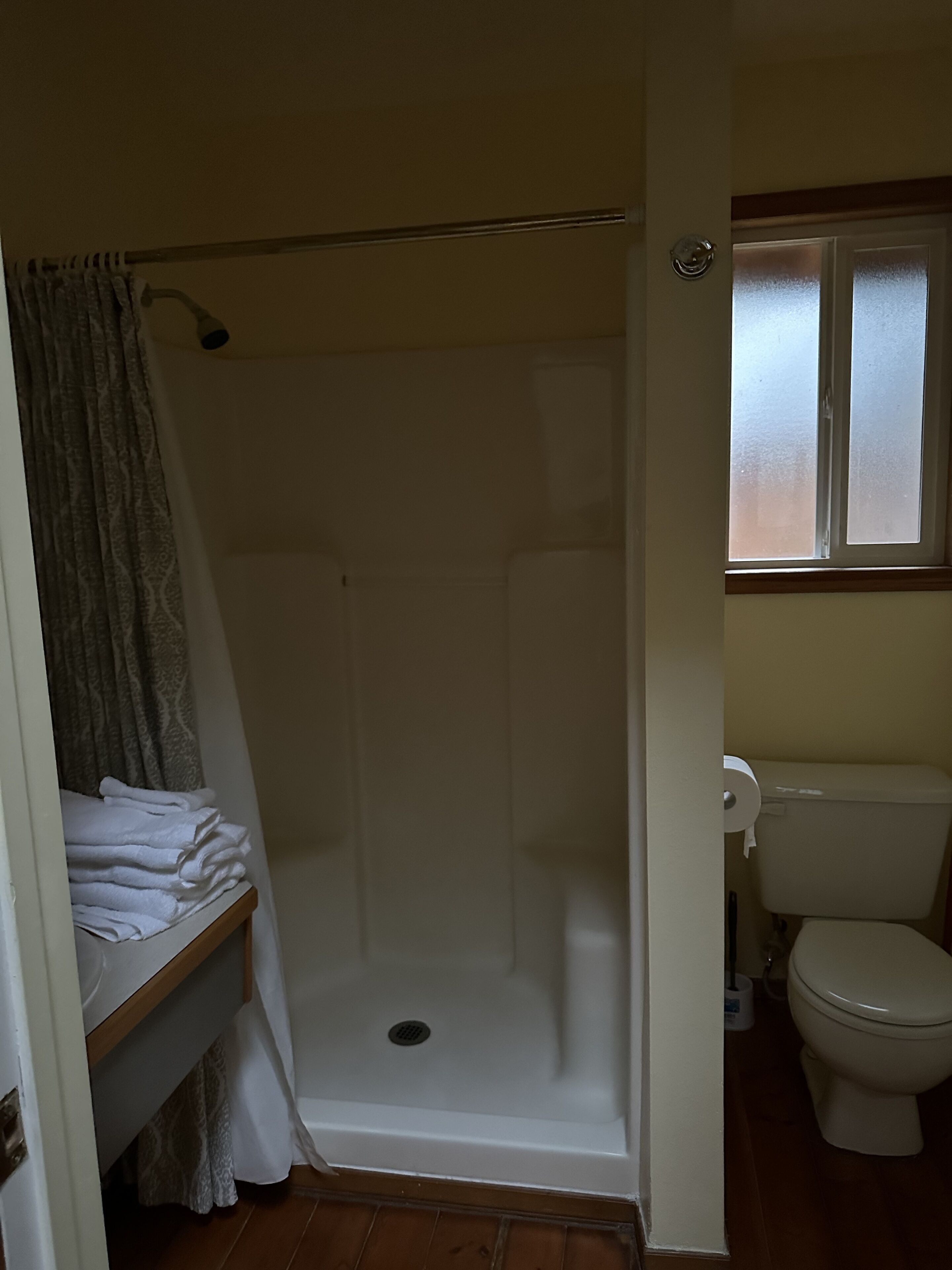 Ein Badezimmer mit Dusche, Toilette und Fenster.