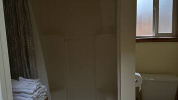 Ein Badezimmer mit Dusche, Toilette und Fenster.