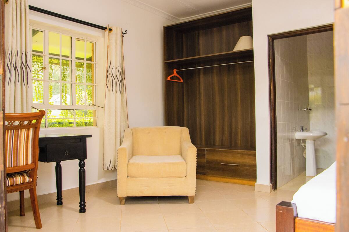 A room with a window, a chair, a wardrobe, and a bed.