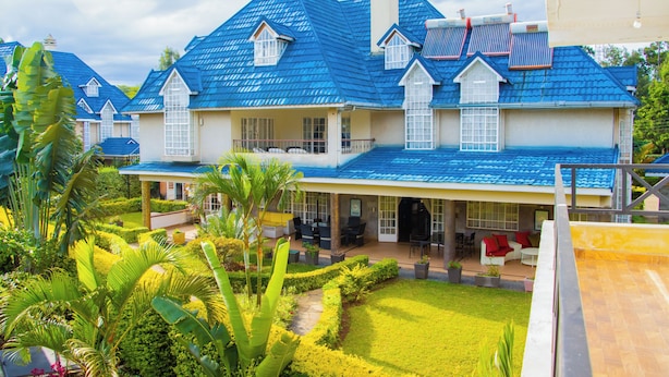 A large house with a blue roof, a covered patio, and a well-maintained garden. - Blixen Resort & Spa  (Nairobi)