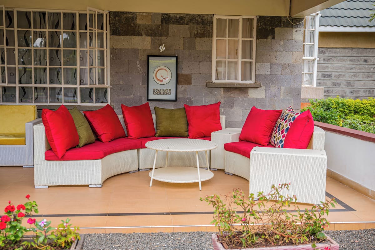 A covered outdoor seating area with a white wicker sofa and a small round table.
