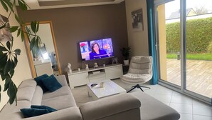 Una sala moderna con un sofá color beige, una mesa de centro blanca y un televisor sobre un mueble blanco.