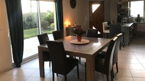 Un comedor con una mesa y sillas, una planta en maceta y vistas al exterior a través de amplios ventanales.