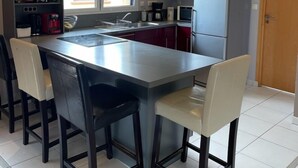 Una cocina moderna con una isla central, taburetes de bar, un refrigerador y un microondas.
