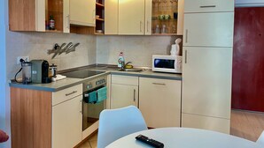 Una cocina moderna con microondas, tostadora y cafetera sobre la encimera, un lavabo y armarios con puertas de vidrio.