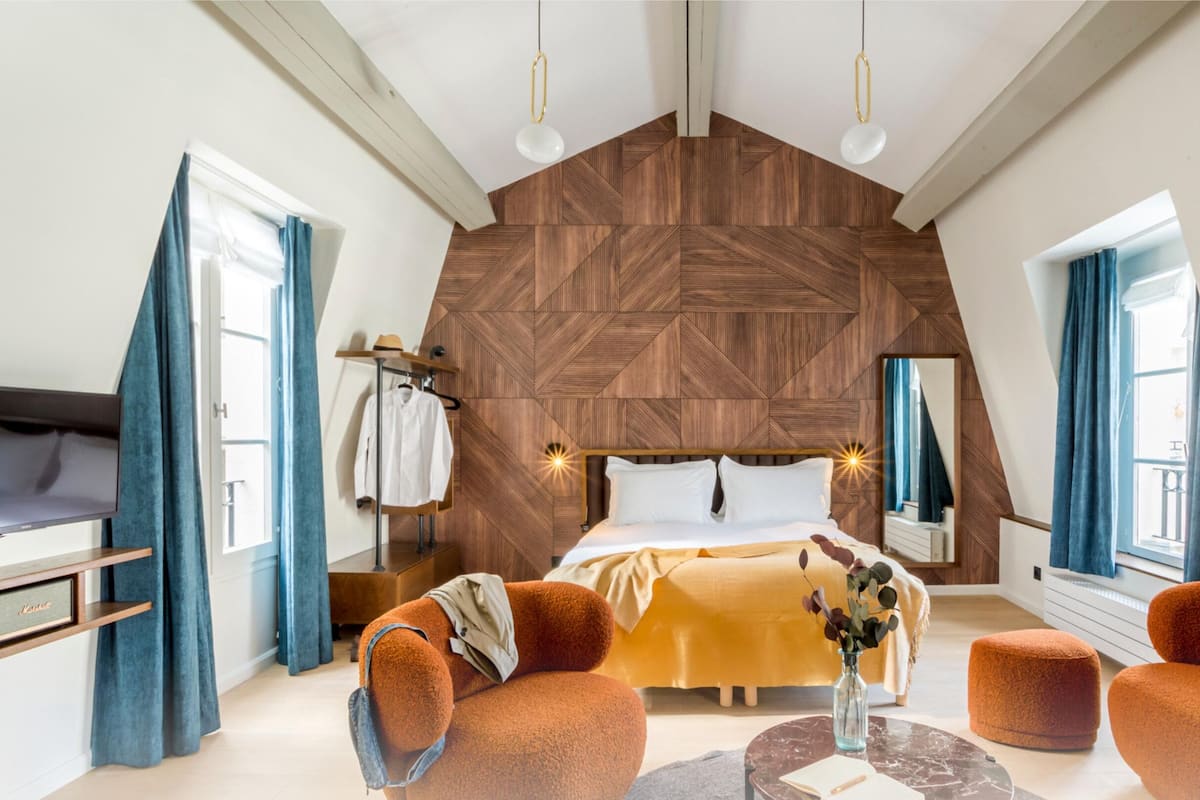 Une chambre moderne avec un toit en croupe, un grand lit, une télévision et des meubles de couleur orange.