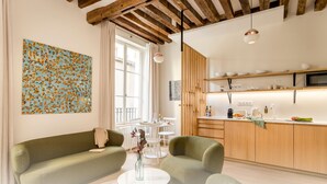 Eine moderne Küche mit Holzschränken, einer weißen Arbeitsplatte und einem Essbereich mit einem grünen Sofa und einem kleinen runden Tisch.
