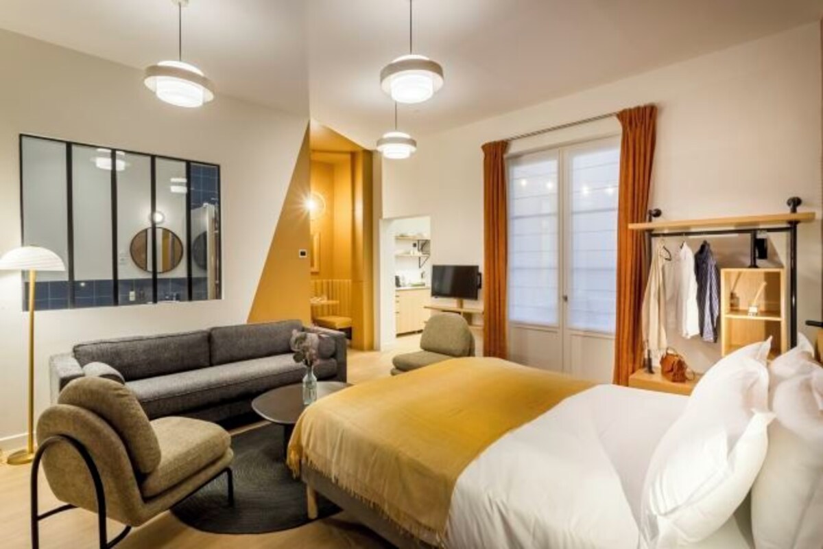 Una habitación de hotel con cama, sofá, televisor y escritorio.