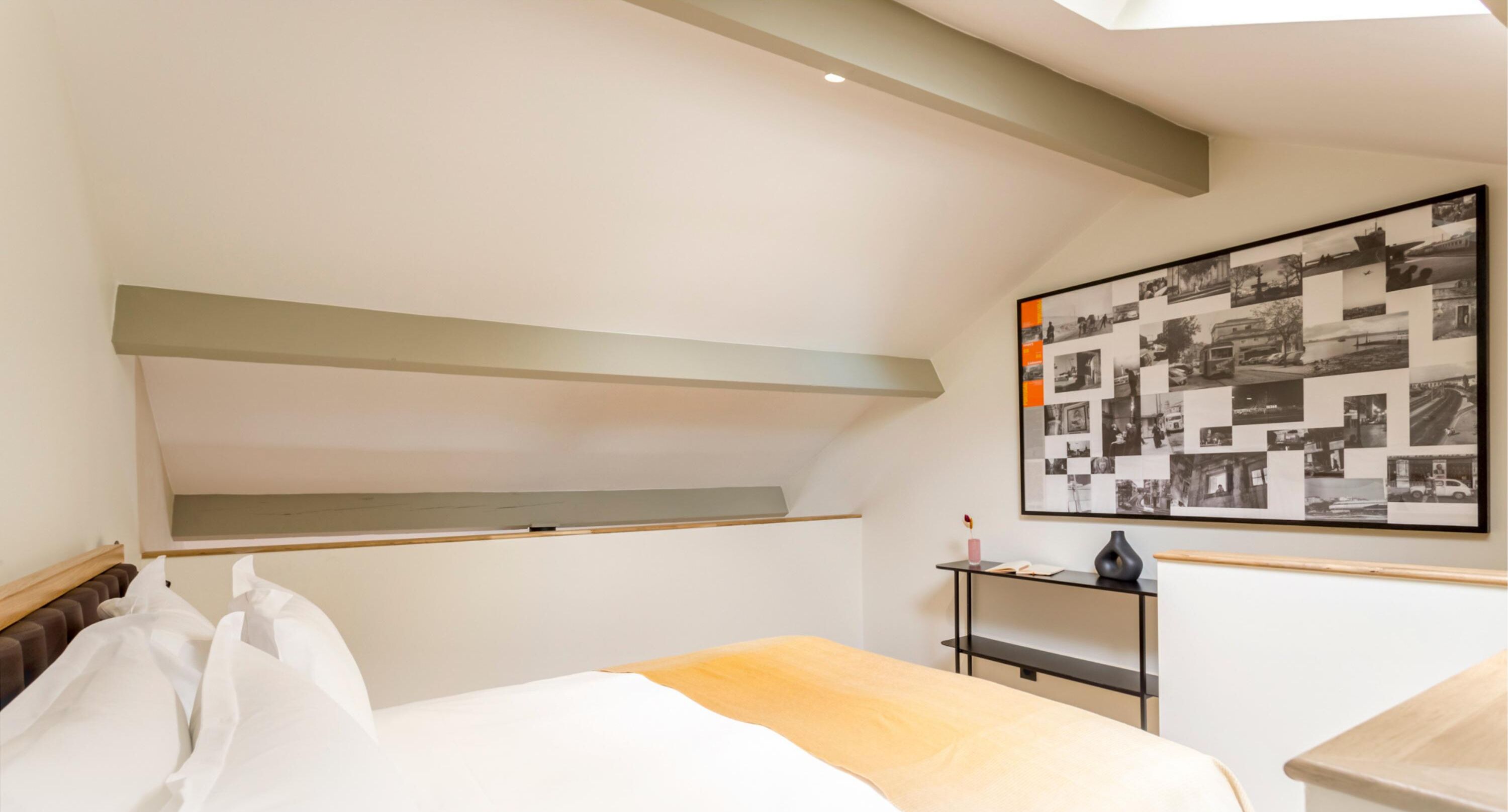 A modern bedroom with a bed, a shelf, a desk, and a wall-mounted picture.