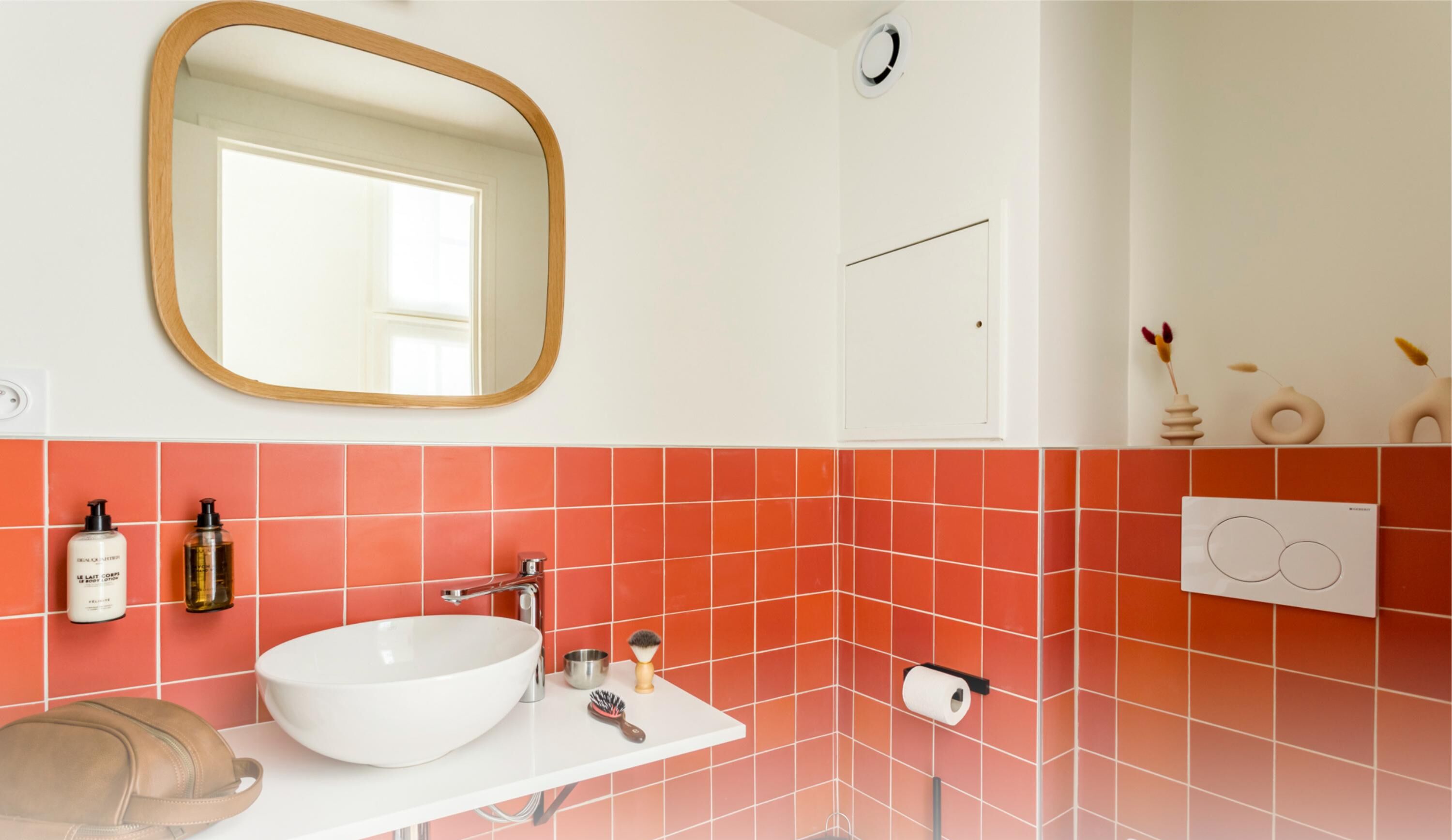 Ein Badezimmer mit einem weißen Waschbecken, einem großen Spiegel und roten Fliesenwänden.