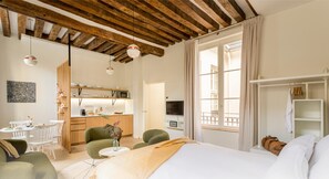 Une chambre d’hôtel moderne avec un plafond en bois, un lit, un coin repas et une cuisine.