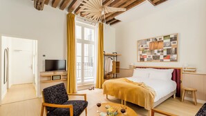 Ein Hotelzimmer mit einem Bett, einem Fernseher, einer Sitzecke mit Tisch und einem fensterbepflanzten Fenster.