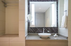 A modern bathroom with a large mirror, a white sink, and a tiled backsplash. - Tanin - Luxurious 2BR Apartment in DAMAC Paramount (Dubai)