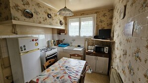 Une cuisine compacte équipée d’une cuisinière à gaz, d’un réfrigérateur, d’un four à micro-ondes et d’un petit évier.