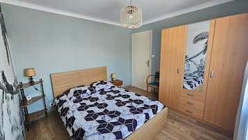 Un dormitorio con cama, armario de madera y una pared decorada con un cuadro.