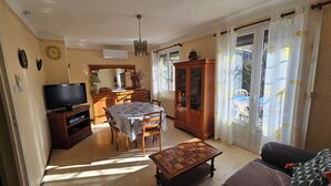 Un salon comprenant un téléviseur, une table à manger et un meuble.