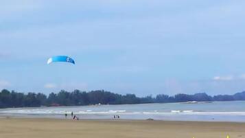 Una playa con una cometa azul volando en el cielo.