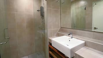 A modern bathroom with a glass shower enclosure, a white sink, and a large mirror.