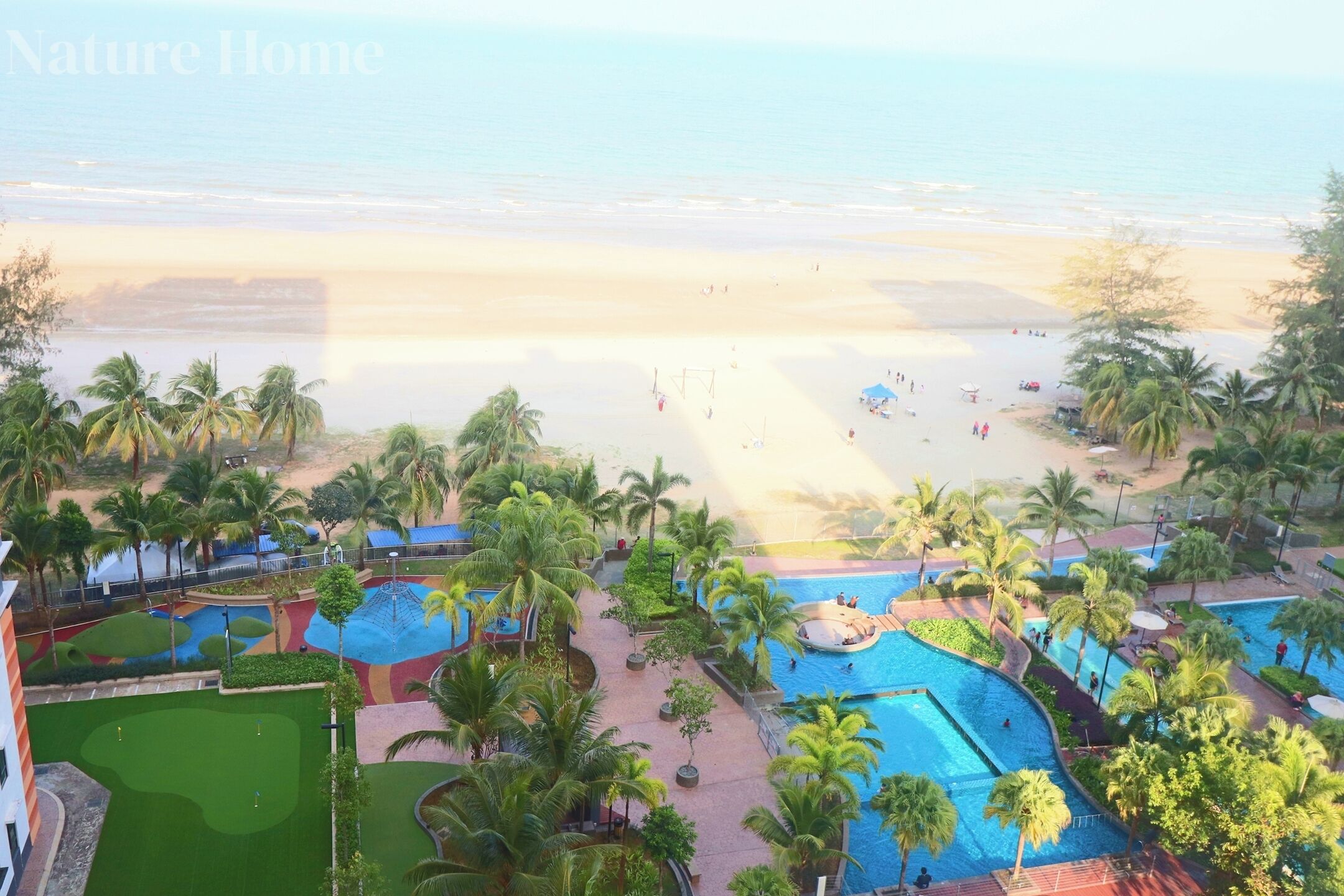 A resort with a beach view, a swimming pool, and palm trees.