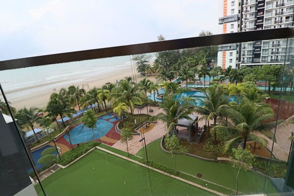 Vista de un resort frente a la playa, con piscina, palmeras y arena.