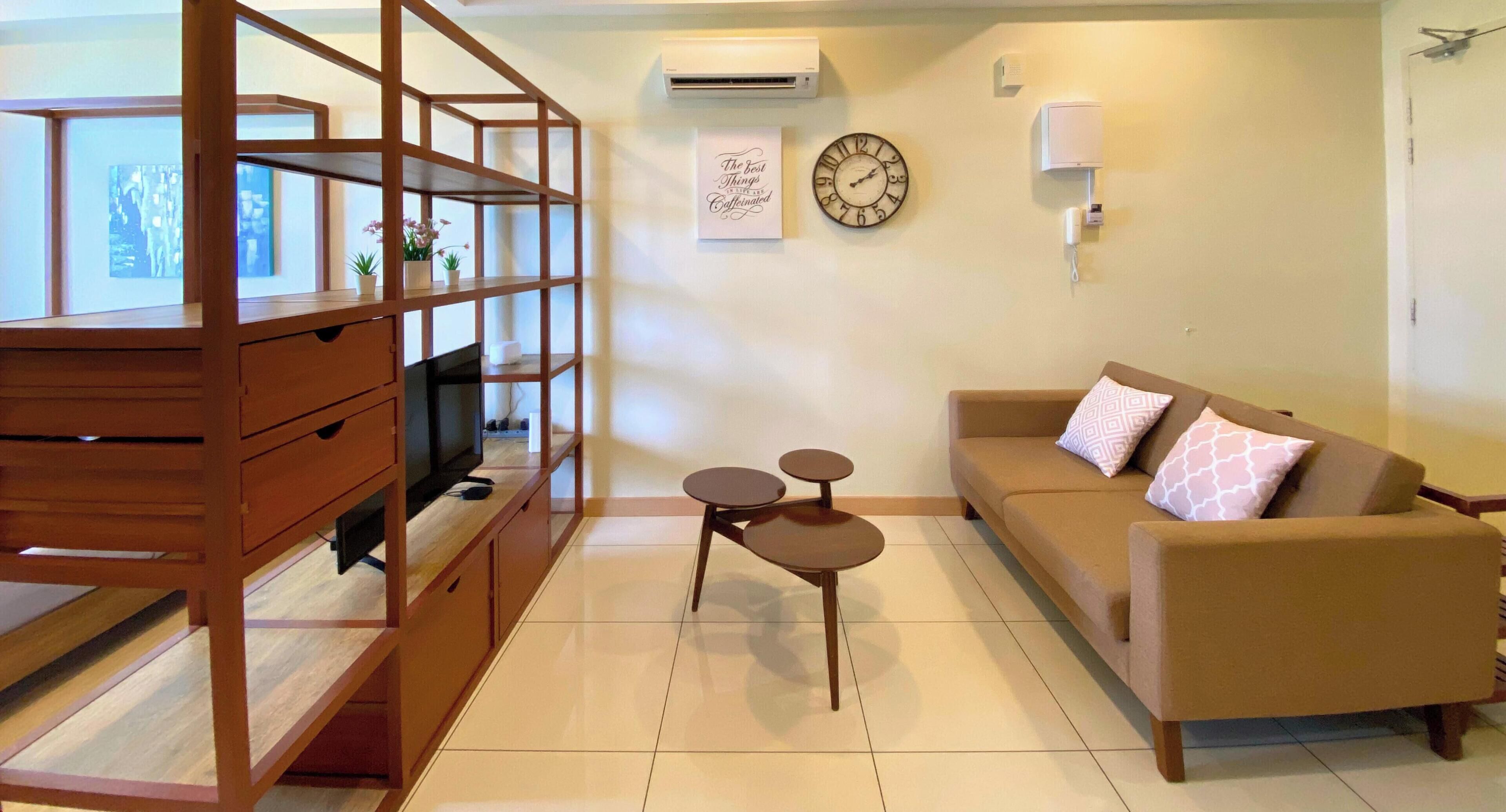 A living room with a sofa, a TV, a wooden shelving unit, and a small table.
