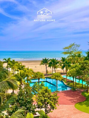 A resort with a pool, palm trees, and a beach view. - Timurbay Seafront Residences NatureHome (Kuantan)