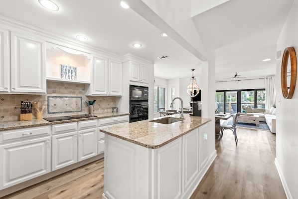 A spacious kitchen with white cabinetry, a granite countertop, and a large island.