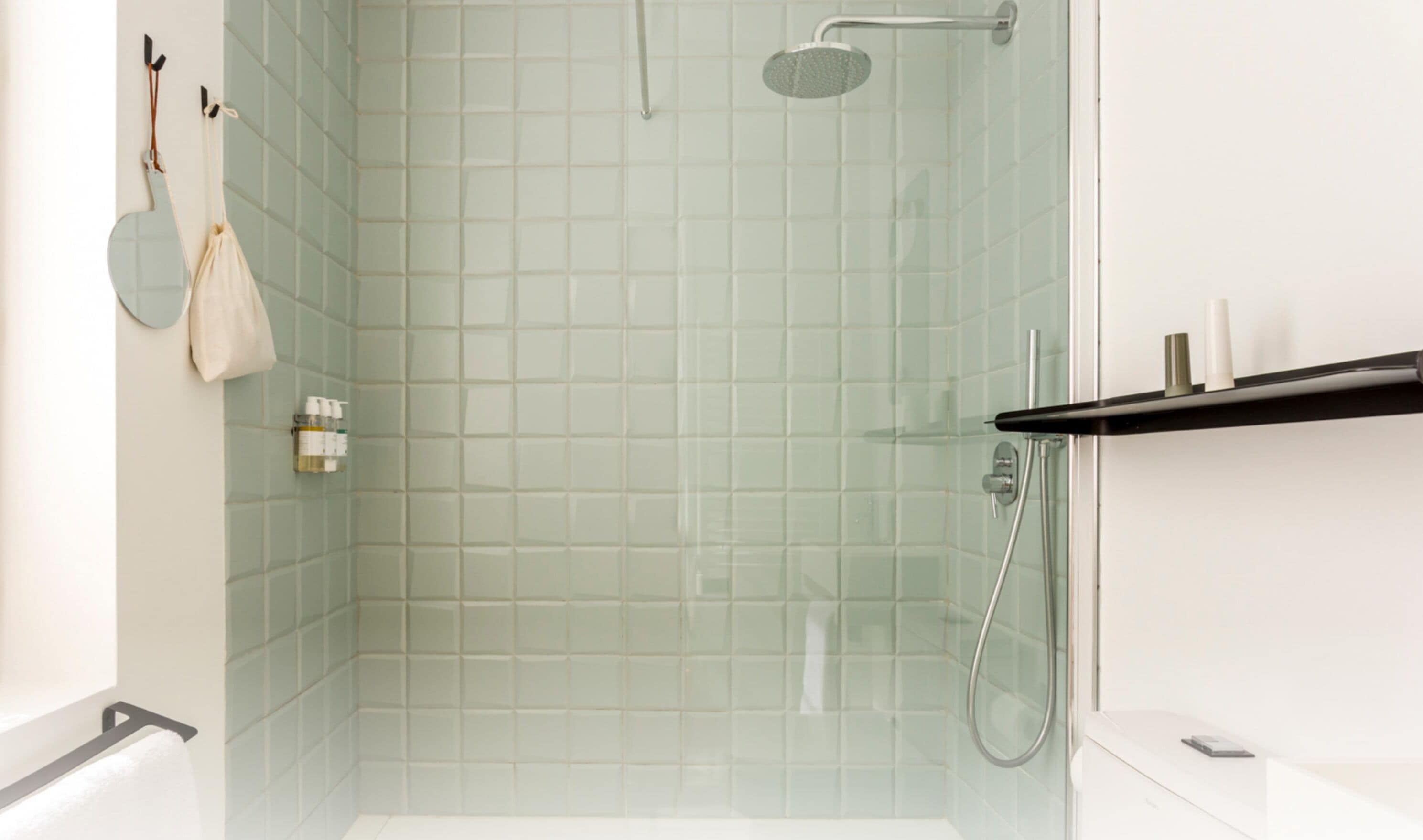 A modern bathroom with a glass shower enclosure, a white bathtub, and a shelf with toiletries.