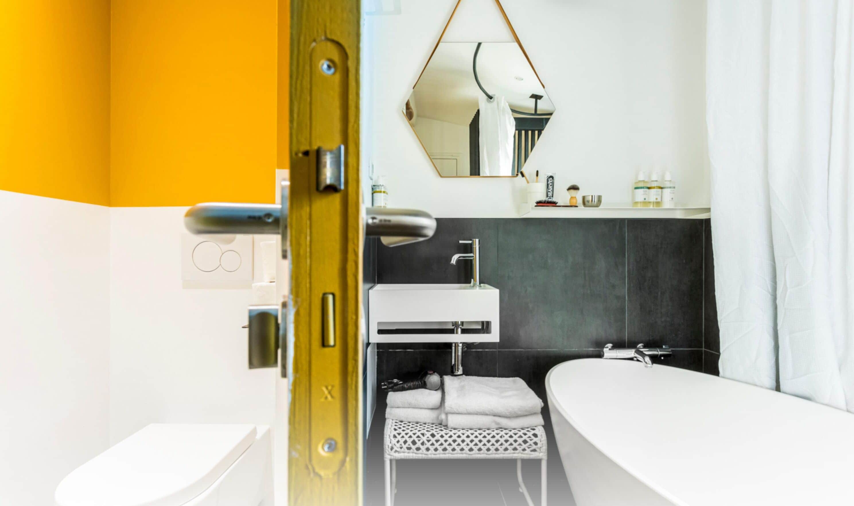 A modern bathroom with a white sink, dark tiled walls, a mirror, and a shower area.