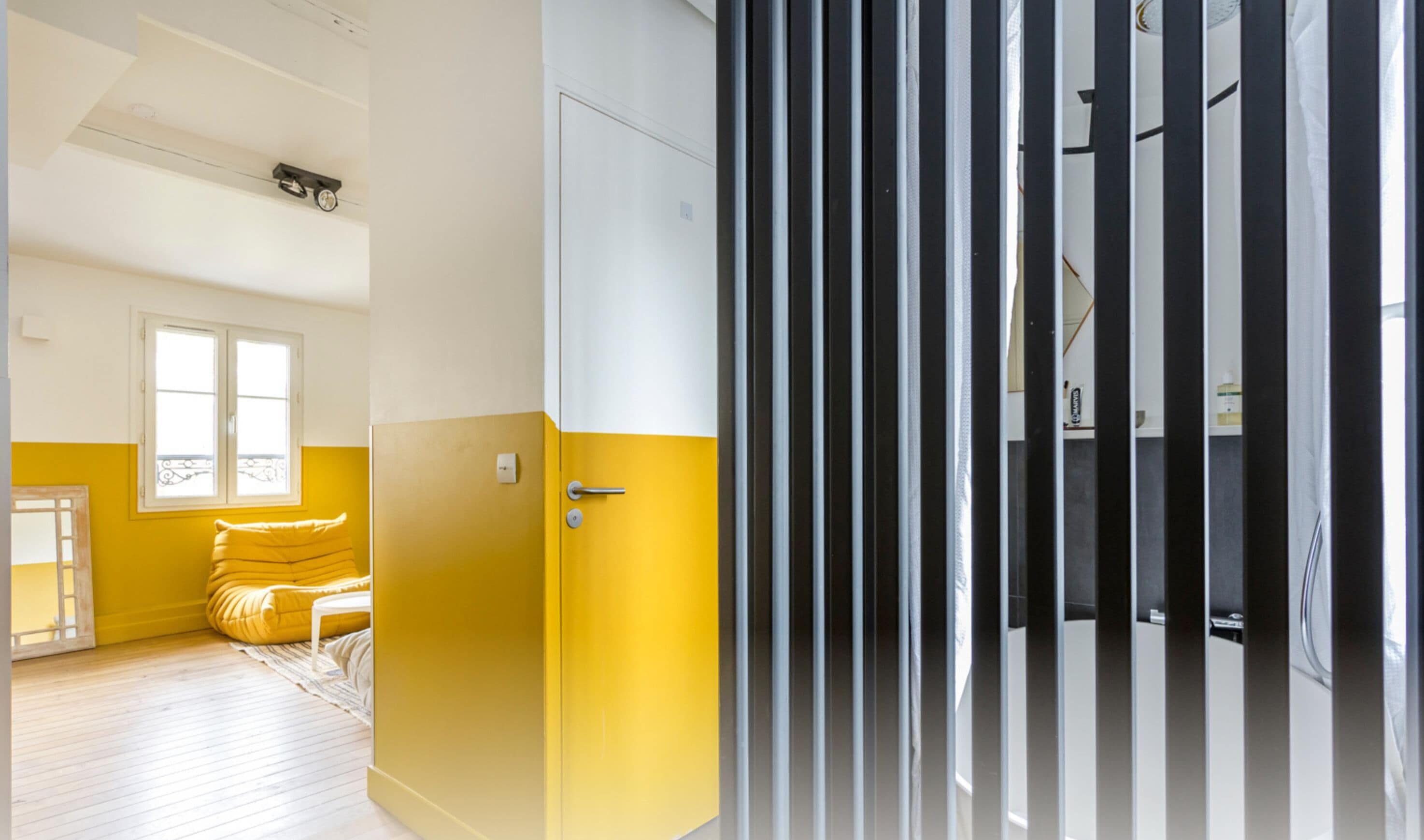 A room with a yellow and white color scheme, a bed with a yellow headboard, a window, and a door with vertical blinds.