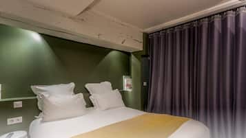 Hotelkamer met een bed, twee kussens, een nachtkastje, een telefoon en een gordijn.