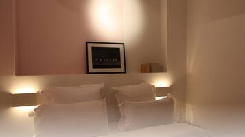 A hotel room with a bed, two bedside tables, a framed picture on the wall, and a nightstand with a lamp.
