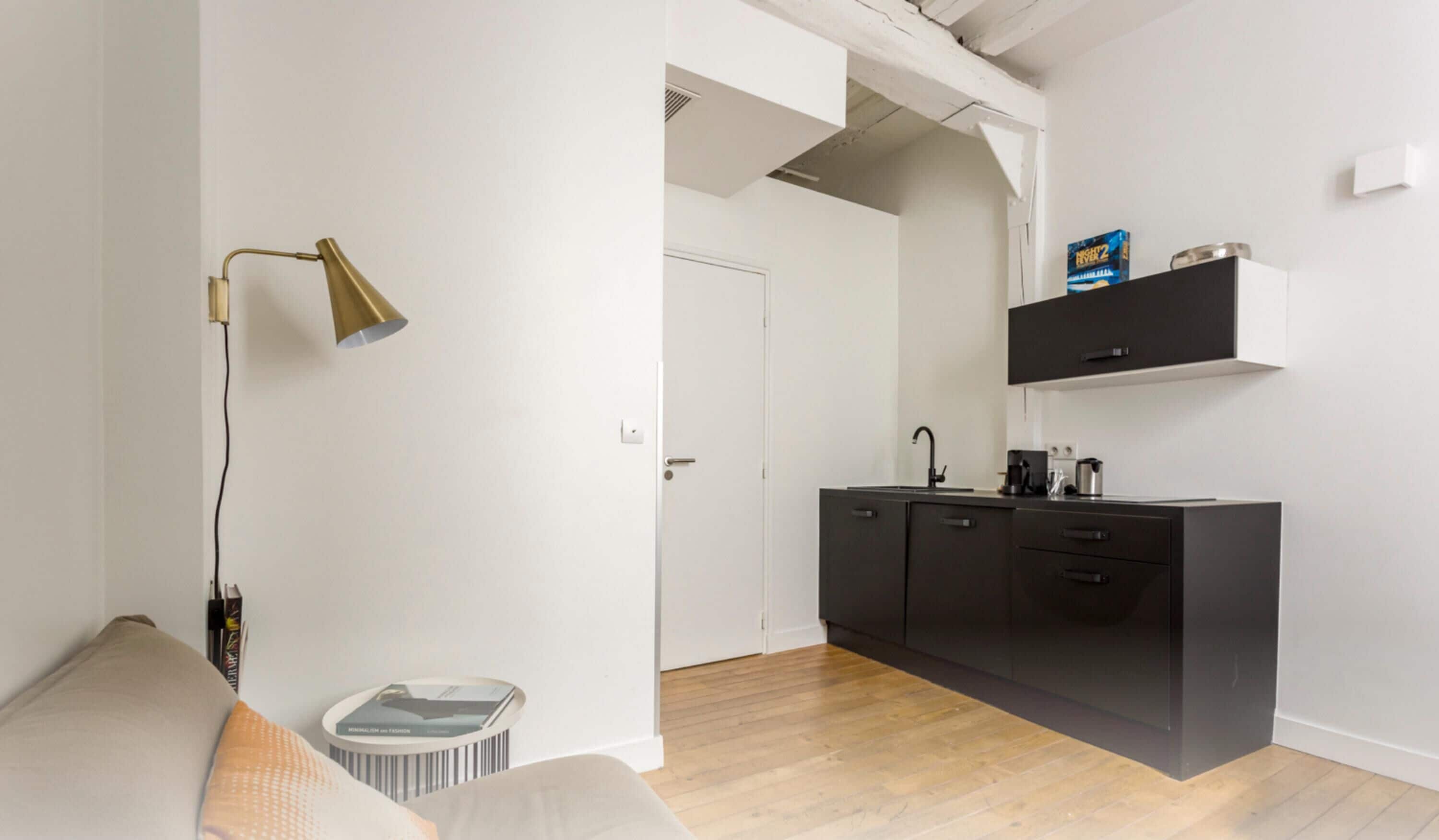 A modern kitchen with a black countertop, a coffee machine, and a shelf above the counter.