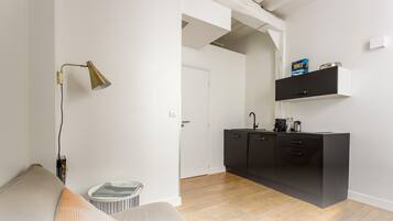 A modern kitchen with a black countertop, a coffee machine, and a shelf above the counter.