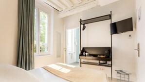 Una habitación de hotel moderna con una cama, un escritorio con televisión de pantalla plana, una mesita y una ventana con cortinas.