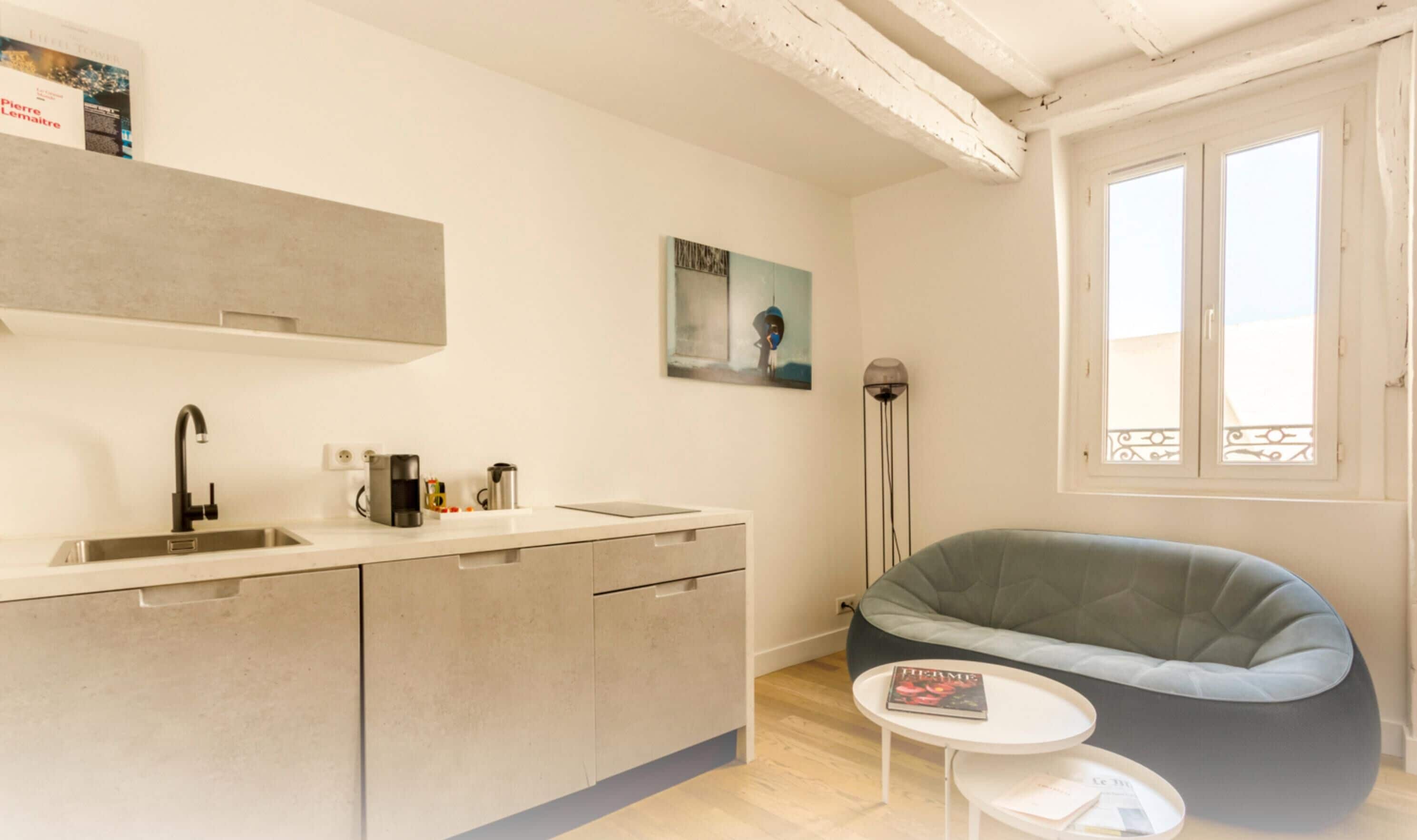 A modern kitchen with a built-in sink, a coffee machine, and a small table with a book.